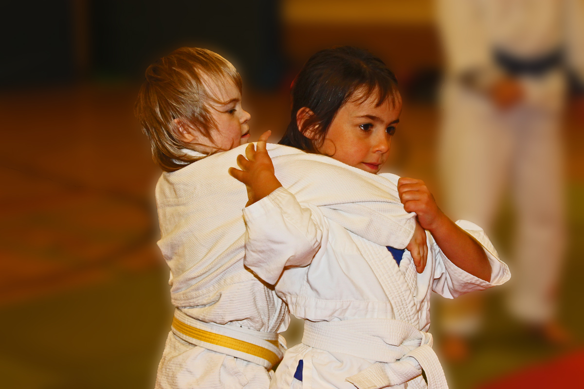 Zwei Kinder in weißen Judo-Anzügen beim Ausüben der Sportart. 