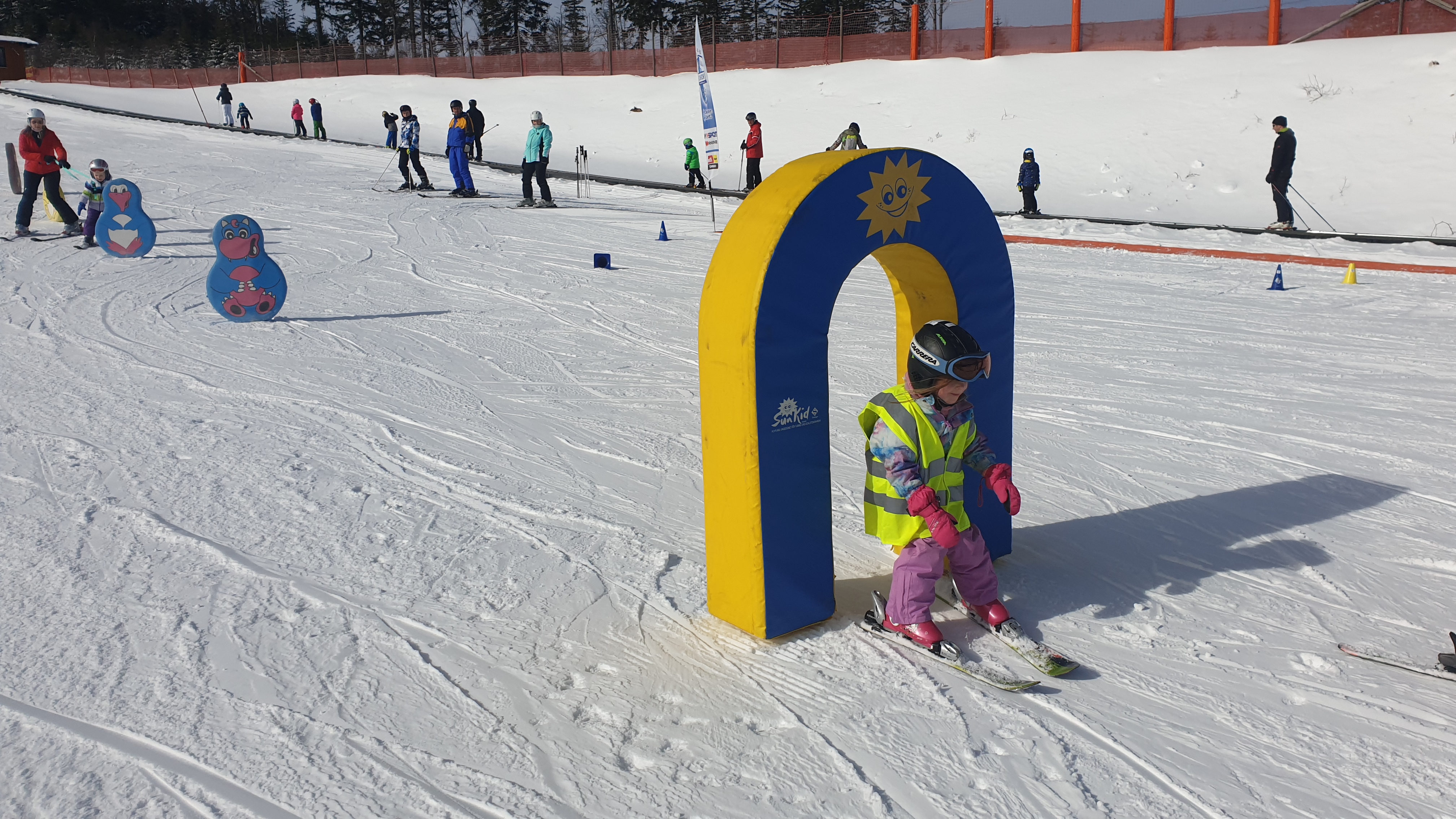 Eine Skifahrerin fährt im ArBär Kinderland durch einen Schaumstoffbogen.