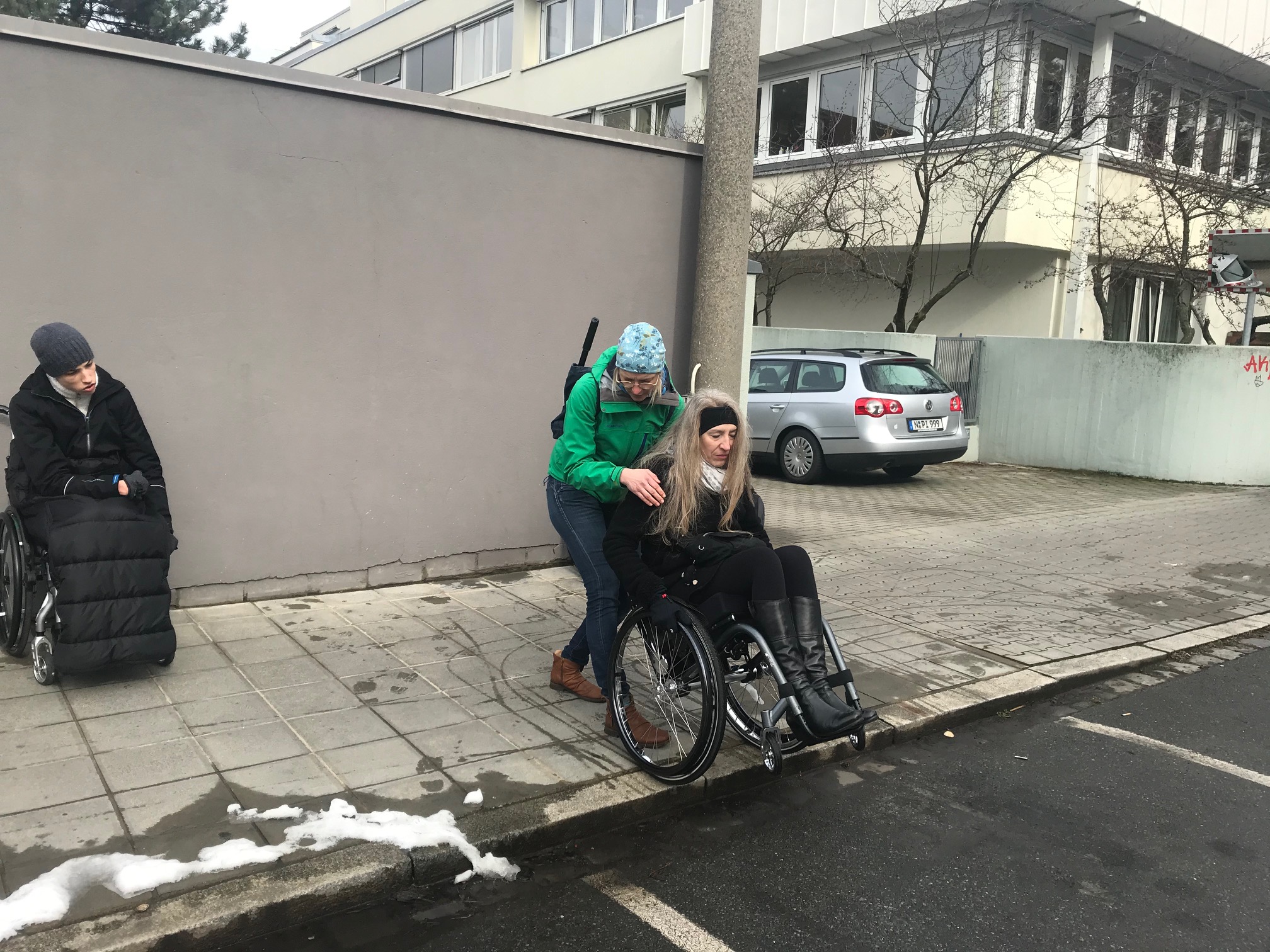 Rollstuhlfahrerin überwindet Bordsteinkante zusammen mit Helferin