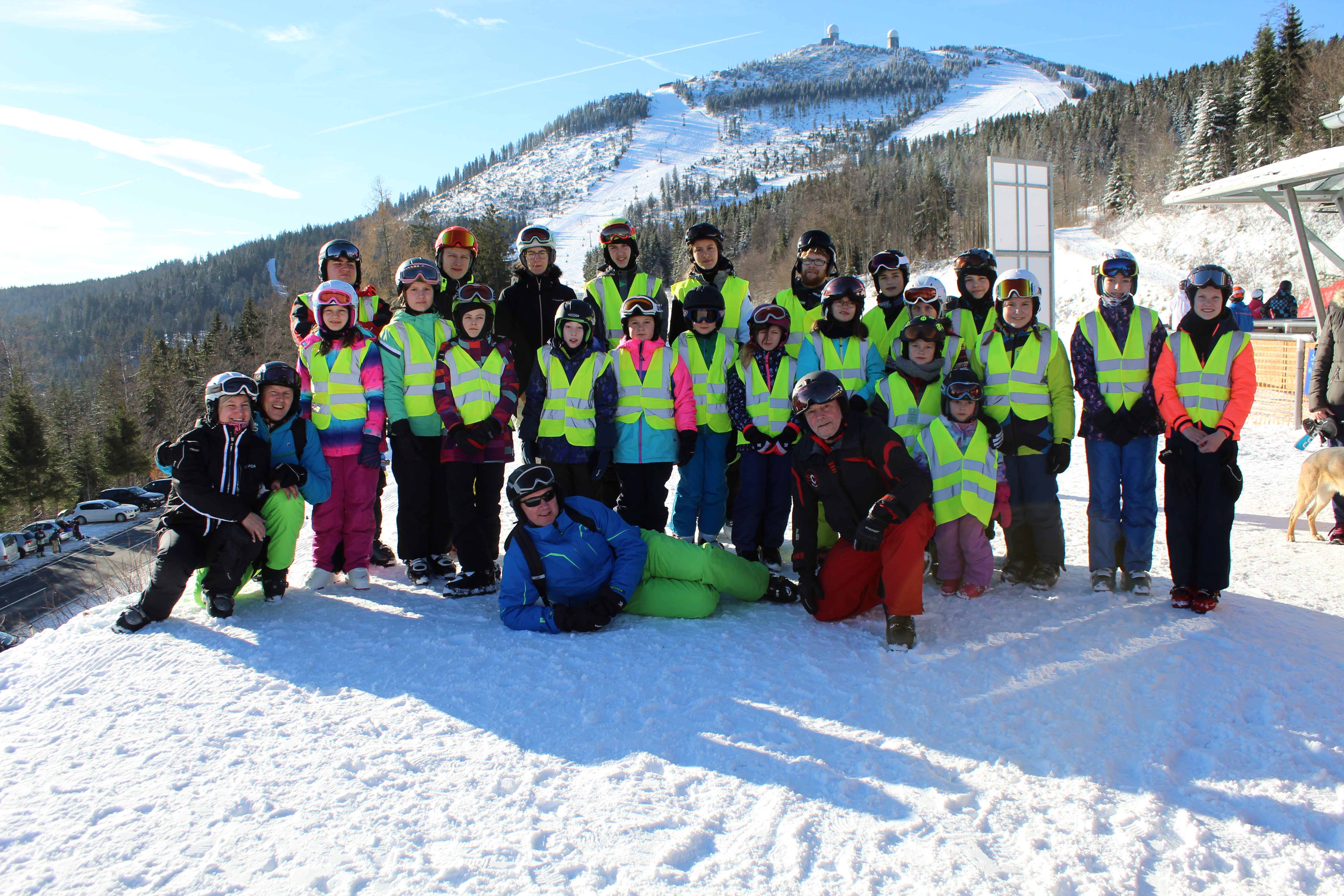 Alle Teilnehmer*innen des Skikurses zusammen mit den Skilehrer*innen und Betreuer*innen bei blauem Himmel im Schnee. 